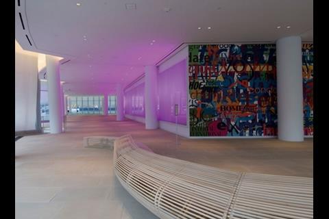 The reception lobby spreads out between a wavy curtain wall and internal murals
